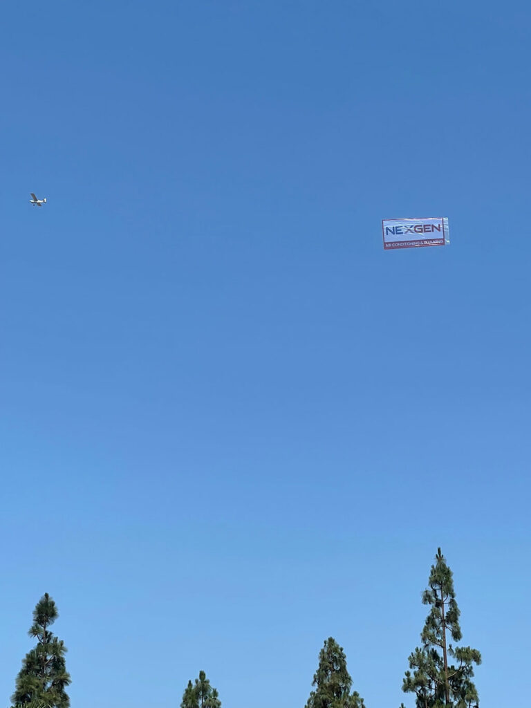 a clear blue sky with a nexgen banner and an airplane